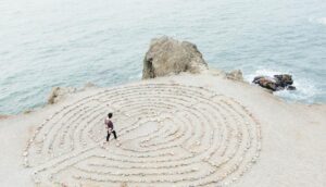 Person practicing labyrinth walking meditation on a beach.