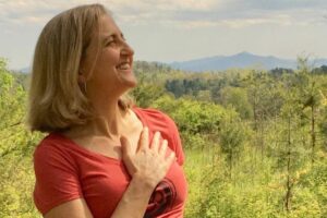 Chronic pain and yoga expert Kristine Weber smiling with her hand on her heart.