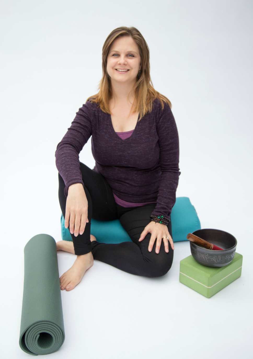 Addie deHilster sitting with Yin Yoga props and a meditation bell