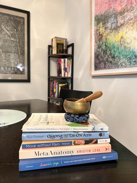 A stack of books and meditation bell on the table for the Mindful Movement Teacher Training.
