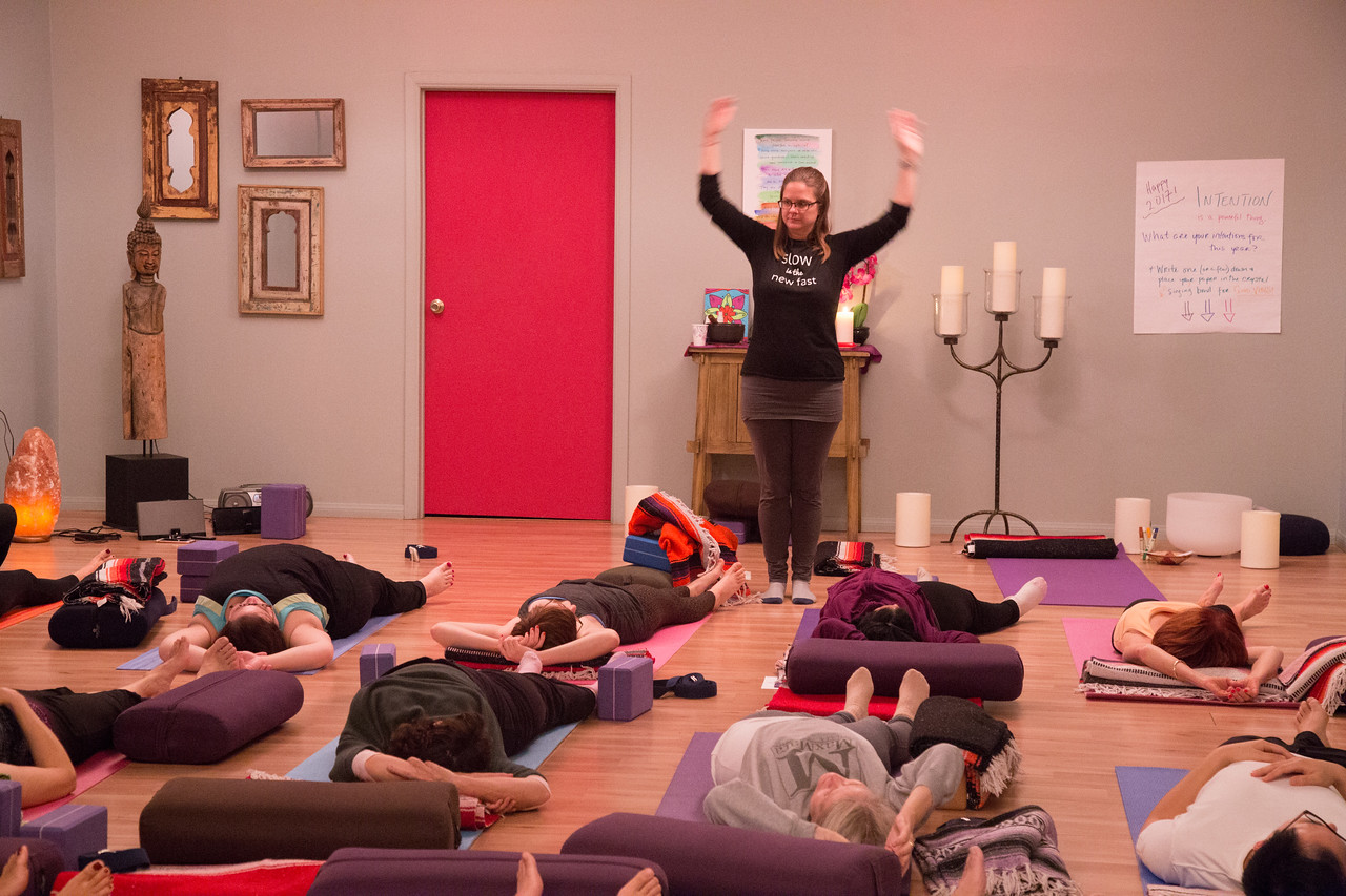 Addie deHilster teaching Yin Yoga Banana Pose to a group of people at her studio.