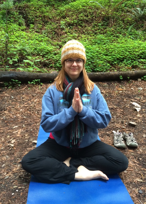 Addie deHilster meditating on a yoga mat in the forest.