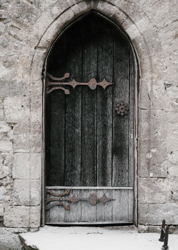 Heavy wooden door in a stone wall, leading to a Library of online mindful movement classes.