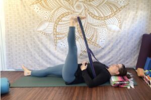 Addie deHilster practicing Yin Yoga Meditation in a reclining leg stretch pose.