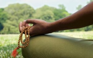 Person sitting outdoors with mala beads, used for ADHD and mindfulness meditation.