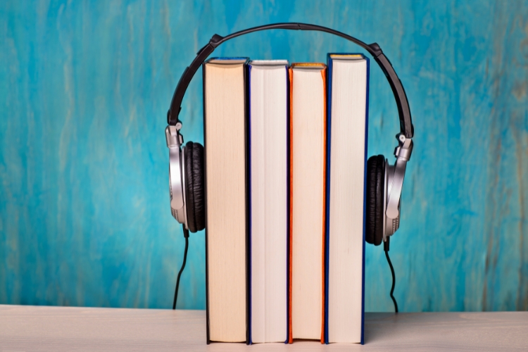 A pair of headphones resting on a set of books, representing the Moved to Meditate Podcast and upcoming book!
