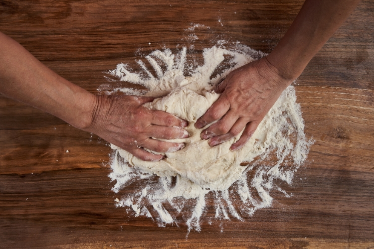 Hands kneading dough for bread, illustrating the Mindfulness Skills of patience and perseverance.