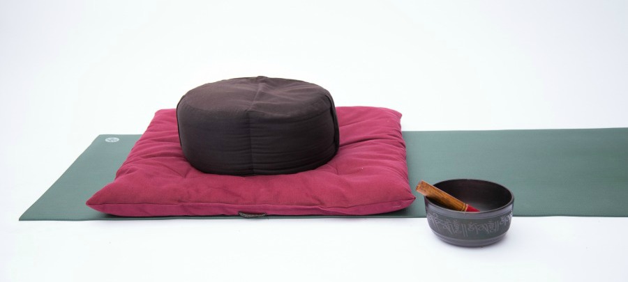 The setup for a Mindful Movement practice, including a meditation cushion on a yoga mat, along with a bell.